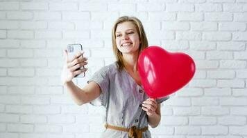 valentine-s-day-concept-smiling-beautiful-woman-in-love-chatting-and-taking-selfie-on-the-mobile-phone-holding-a-big-red-heart-balloon-free-video